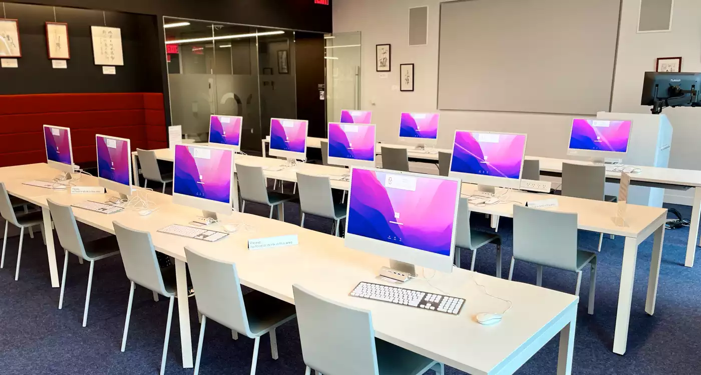 Three rows of tables with several Apple workstations on each table.