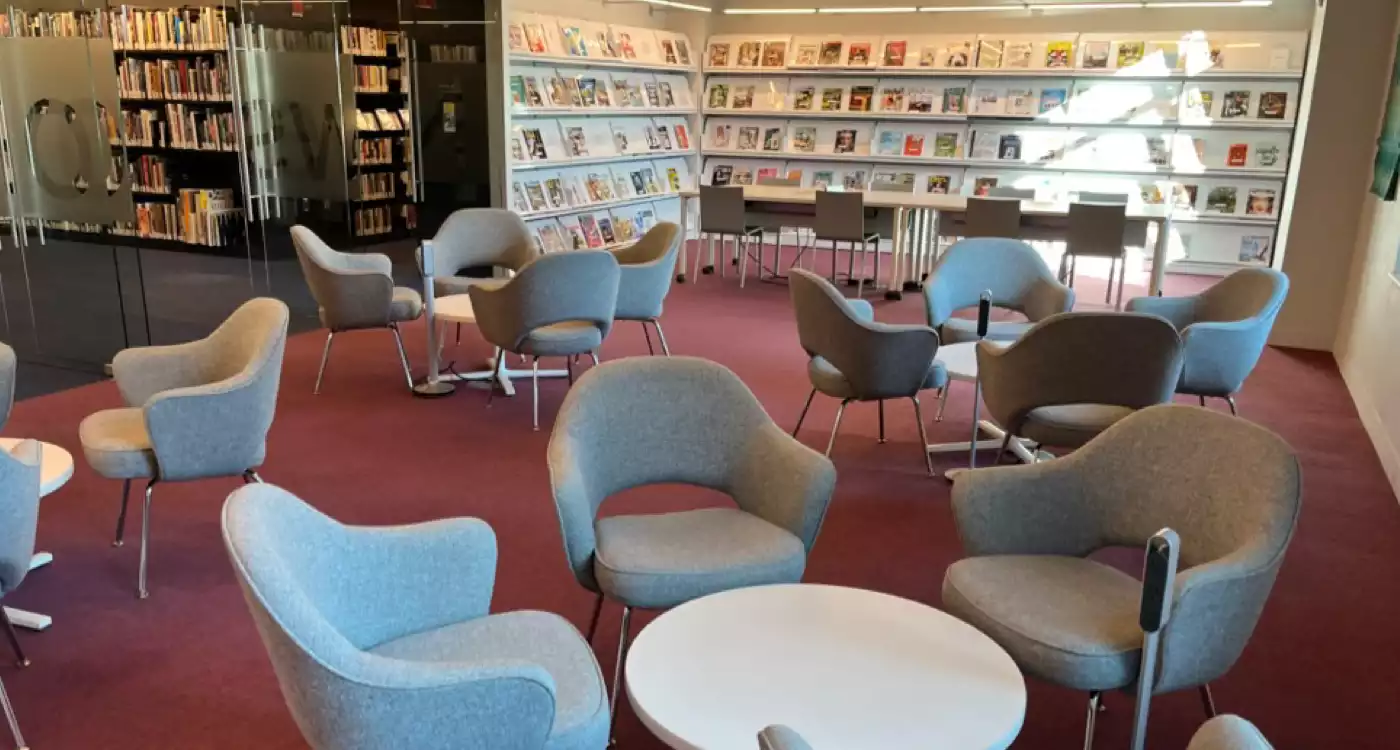 Low tables and chairs with magazines on shelves against the wall.