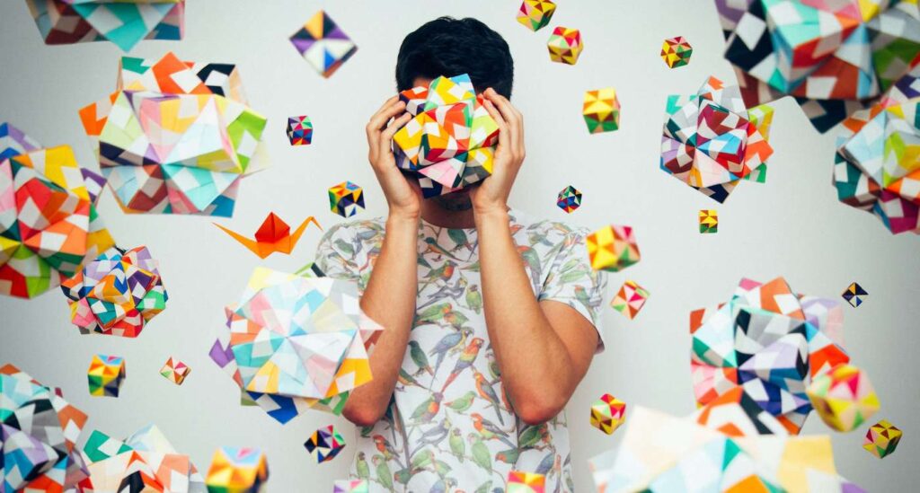 Person holding a origami geometric ball and surrounded by floating origami forms
