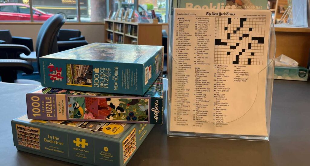 Image of three stacked jigsaw puzzles next to a crossword puzzle.