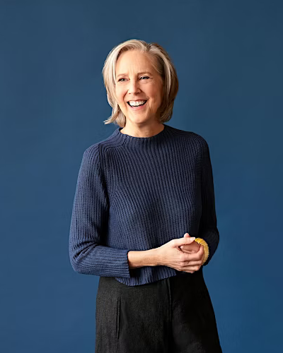 Photo of the author, Mary Roach standing with a blue background.