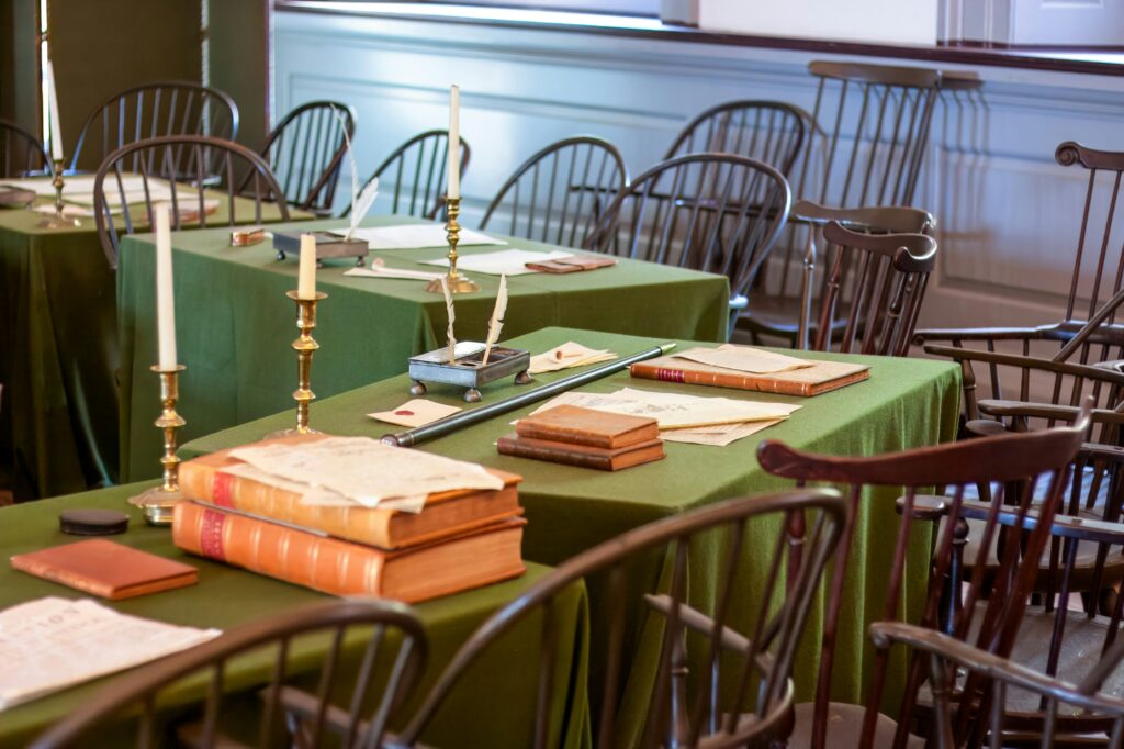 Table and chairs with old books, candles and quills.