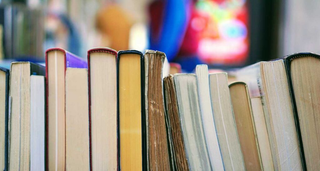 Image of books sitting horizontally in a row.