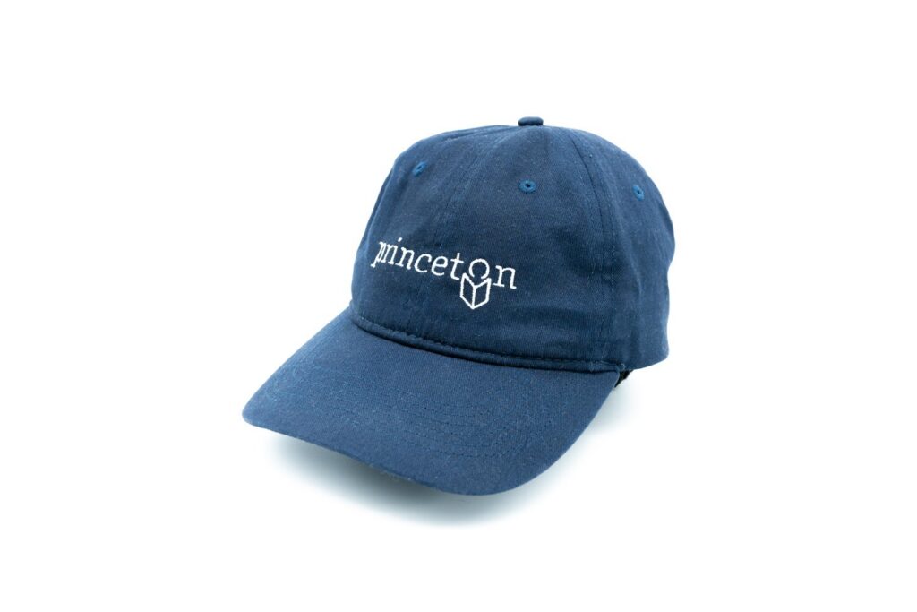 blue baseball cap with the Princeton Public Library logo embroidered on the front.