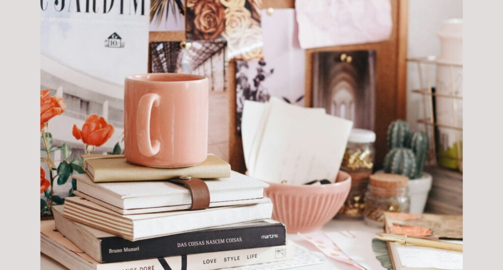 A coffee mug and books sitting on a desk.