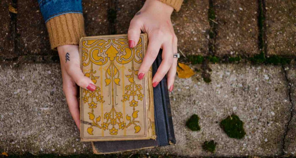 Image of hands holding hardcover books, displaying a decorative cover.
