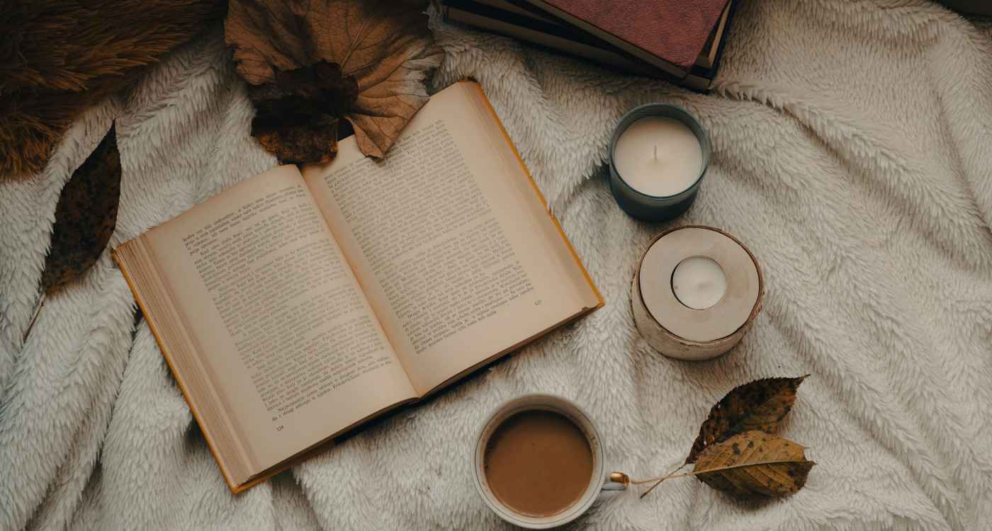 Image of an open book surrounded by candles and autumn leaves